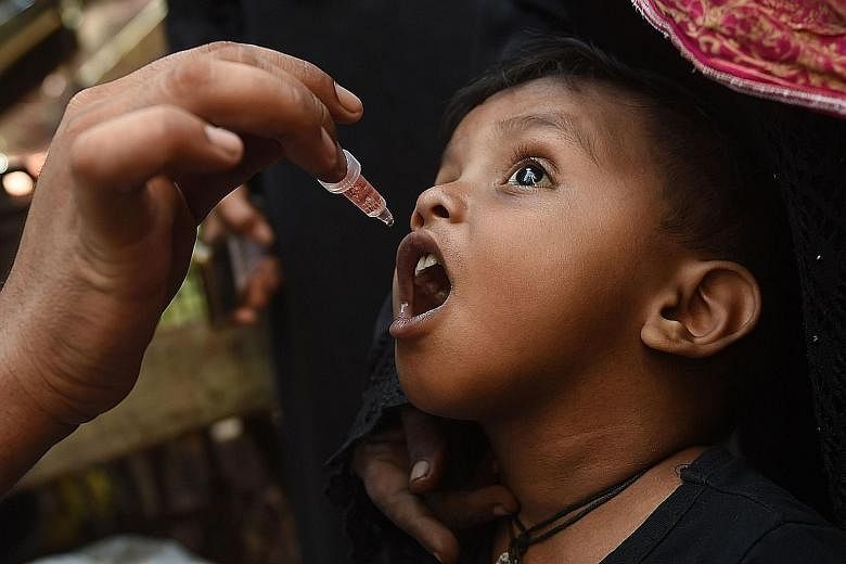 A child in Pakistan getting the polio vaccine. The writer says that perhaps we should use our current low-transmission breather to get vaccinated against Covid-19, when the treatment is available in Singapore, so that we can emerge stronger.