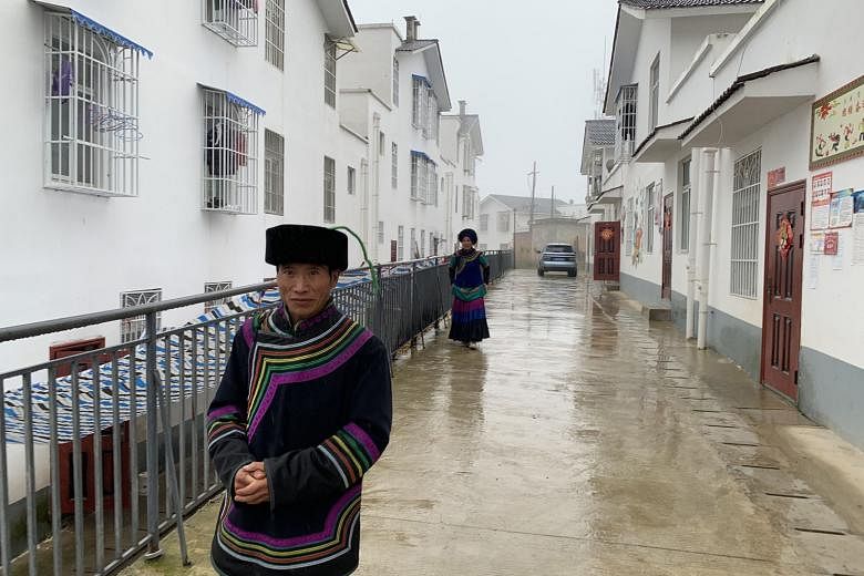 Right: Villagers walking down an alley between rows of new houses built by the Chinese government - as part of its anti-poverty campaign - in Xujiashan village in Liangshan Yi Autonomous Prefecture's Ganluo county. Villagers used to live in mud huts.