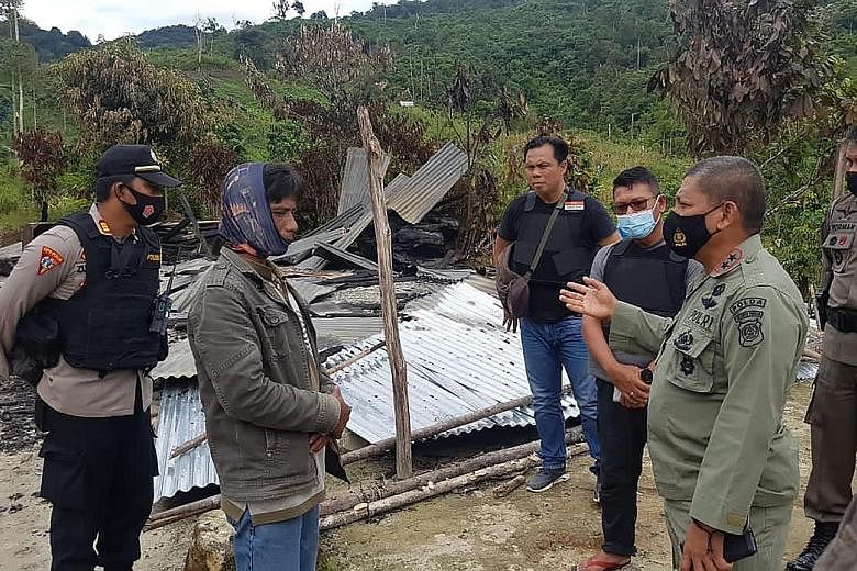 Police officers at the site of an attack in Lembantongoa village, Central Sulawesi, in which four men were killed and homes torched.