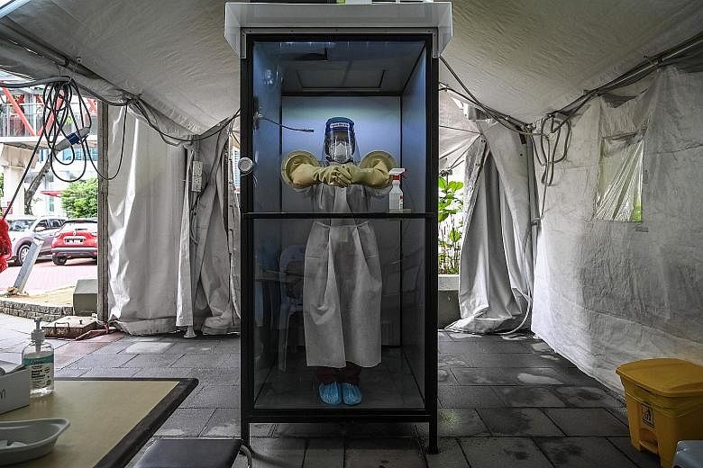 A health worker in a non-contact chamber used to take Covid-19 swab samples at a medical centre in Selangor. The Malaysian government is to conduct Covid-19 tests on 1.7 million foreign workers in the country. PHOTO: AGENCE FRANCE-PRESSE