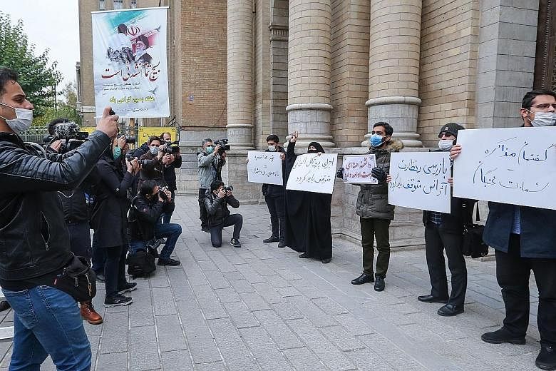 Students of Iran's Basij paramilitary force being photographed by journalists yesterday holding up placards during a rally in front of the foreign ministry in Teheran to protest against the killing of nuclear scientist Mohsen Fakhrizadeh on Friday. P