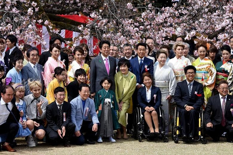 Mr Shinzo Abe and his wife Akie (both centre) posing with entertainers and athletes during a cherry blossom viewing party hosted by the then Prime Minister in Tokyo in April 2017.