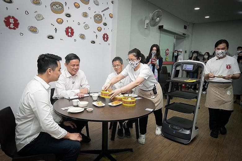Minister for Trade and Industry Chan Chun Sing having dim sum with Swee Choon Tim Sum Restaurant's third-generation owner Ernest Ting (far left) and second-generation owner Tony Ting during a visit to the eatery yesterday. Mr Chan cited Swee Choon as
