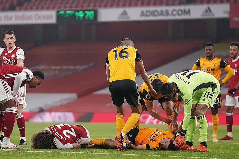 Arsenal's David Luiz and Wolves' Raul Jimenez lying on the pitch after they banged heads in the Premier League match in London on Sunday. The latest incident reignited debate about whether football is taking head collisions seriously.
