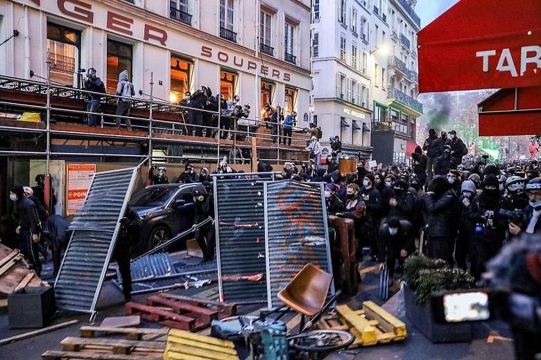 People using street barriers as protective shields during a protest in Paris last Saturday against the French government's draft law which would criminalise the publication of images of on-duty police officers. PHOTO: AGENCE FRANCE-PRESSE