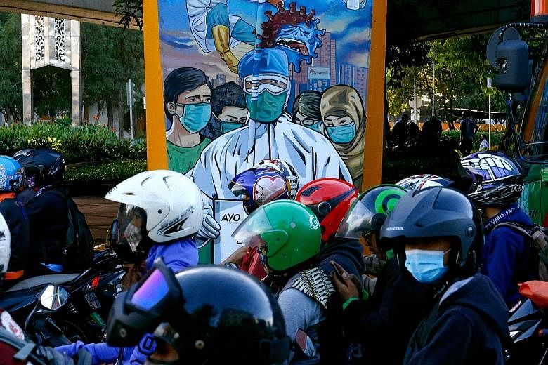 Motorcyclists passing a mural promoting awareness of the Covid-19 outbreak in Jakarta. The country remains the worst hit in South-east Asia with the number of confirmed cases at 549,508 as of yesterday, with 17,199 deaths.