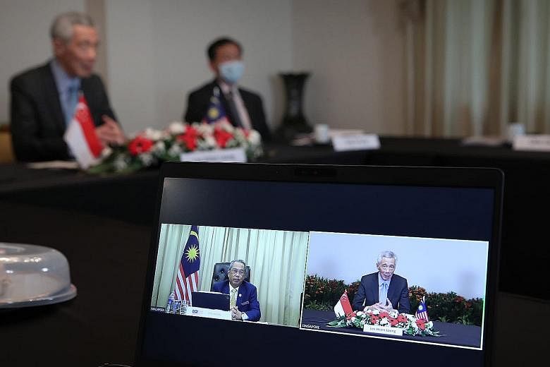 Prime Minister Lee Hsien Loong and Malaysian PM Muhyiddin Yassin in a video conference yesterday. Also in attendance during the call were Transport Minister Ong Ye Kung (in background) and Foreign Minister Vivian Balakrishnan.