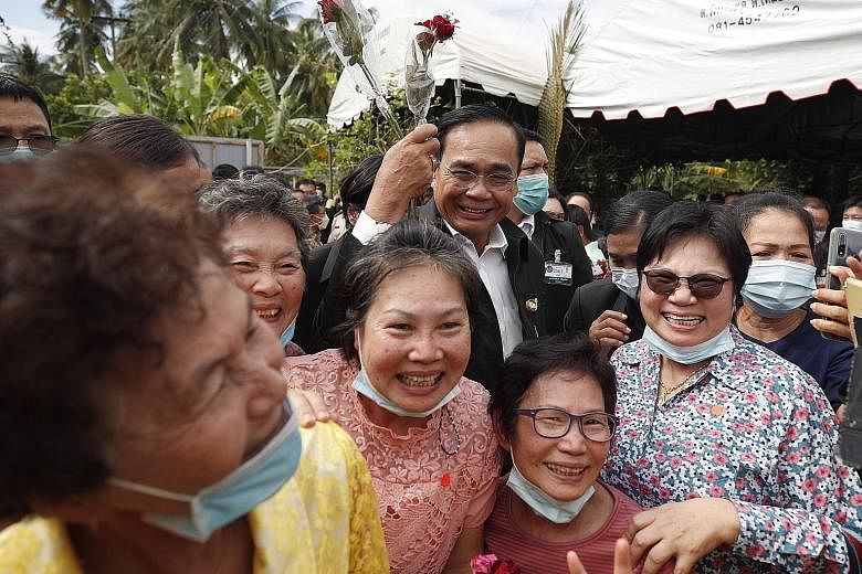 Prime Minister Prayut Chan-o-cha with villagers during a visit yesterday to Samut Songkhram province. He retired as army chief in 2014 but he and his family have continued to stay in the army quarters for security reasons.