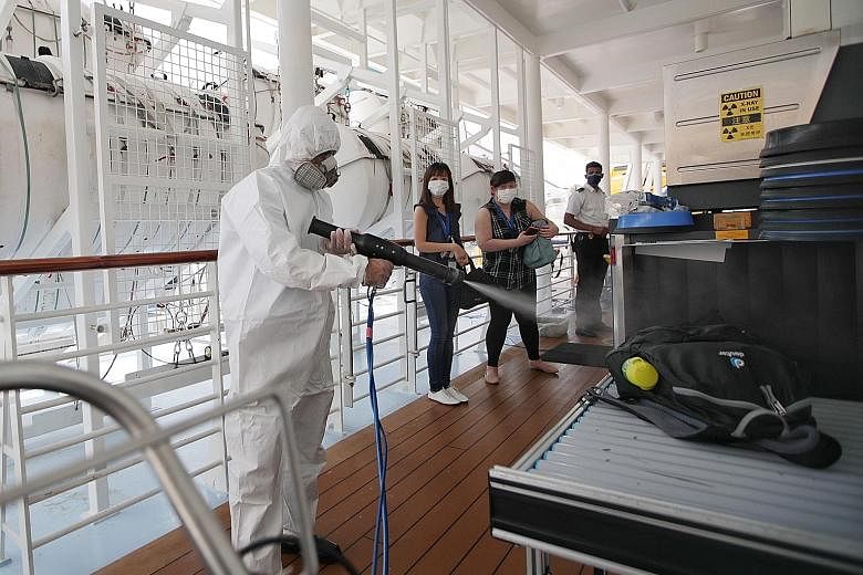 Workers disinfecting passenger suitcases before the Quantum of the Seas cruise to nowhere yesterday. Apart from deep sanitation between sailings, the ship's corridors and public areas are disinfected daily. Frequently touched areas in lifts, escalato