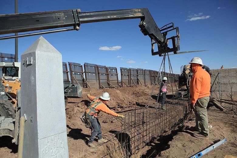 Workers rushing to finish building a metal wall between Columbus, New Mexico, in the United States, and Puerto Palomas in Chihuahua, Mexico, on Wednesday. US President Donald Trump's promise to build a wall along the US-Mexico border was the centrepi