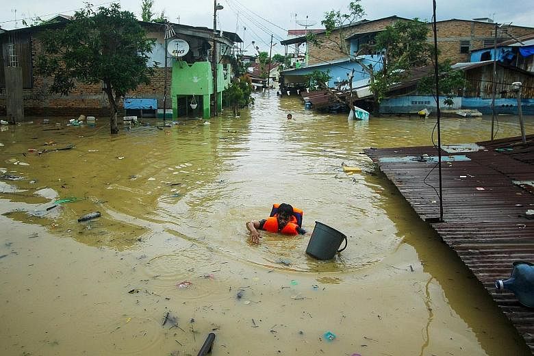 An Indonesian rescuer wading through flood waters caused by overnight heavy rain in Medan yesterday. Heavy rainfall since Thursday has caused water levels to rise around North Sumatra's biggest city, with more than 2,700 homes flooded. Local news rep