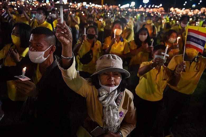 Royalist supporters holding candles and the Thai national flag at a ceremony in Bangkok last night to commemorate the birthday of the late King Bhumibol Adulyadej. Many Thais regard King Bhumibol, who died in 2016 after reigning for seven decades, as