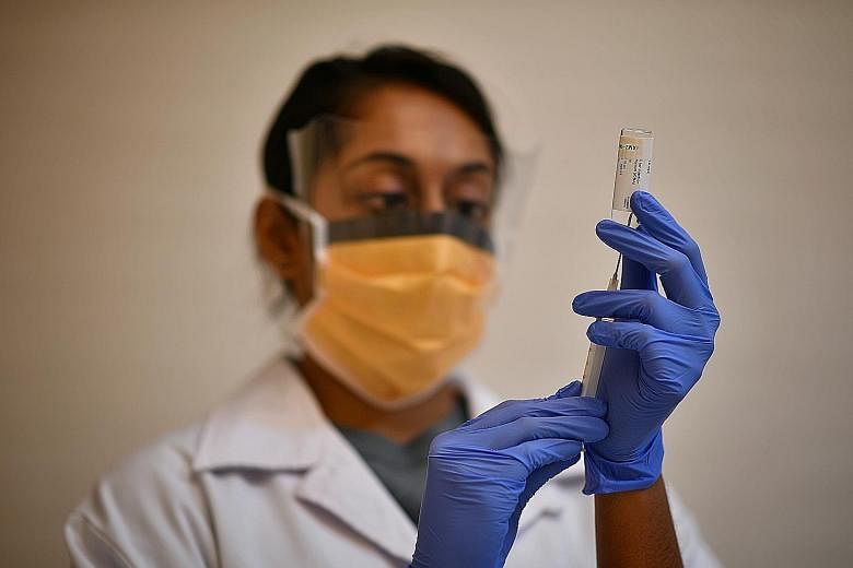 A nurse preparing a Covid-19 vaccine for an early-stage clinical trial at SingHealth's Investigational Medicine Unit. Widespread vaccinations should come by the middle of next year, and with them, a faster return to business activity. The industry's 