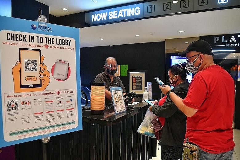 People using the TraceTogether app to check in at their specific movie halls in Cathay Cineplex at JEM.