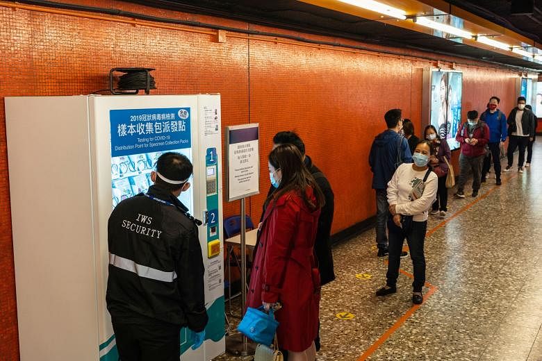 People queueing to collect Covid-19 test kits (below) from a vending machine at a train station on Hong Kong yesterday. From tomorrow till Dec 23, there will be no dine-in services between 6pm and 4.59am the next day. Businesses such as gyms, sports 