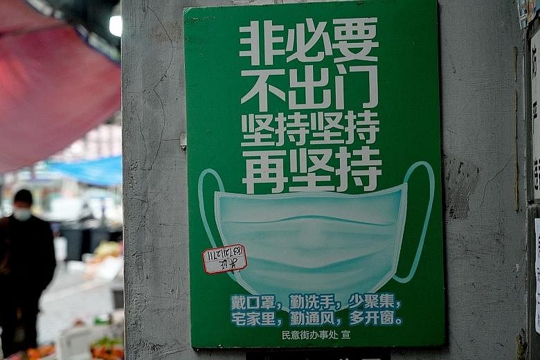Above: A pharmacy in Wuhan where a table has been set up in front of the counter to ensure adequate social distancing. Left: A poster in the city telling people not to go out unless necessary, to have self-discipline and to wear a mask. PHOTOS: M. IS