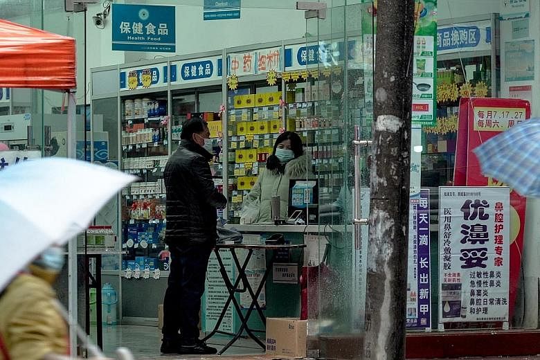 Above: A pharmacy in Wuhan where a table has been set up in front of the counter to ensure adequate social distancing. Left: A poster in the city telling people not to go out unless necessary, to have self-discipline and to wear a mask. PHOTOS: M. IS