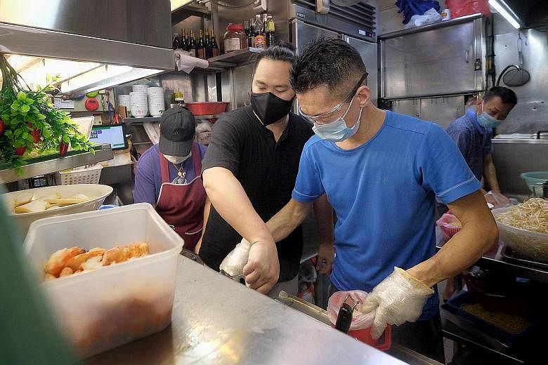 Top and above: Mr Tan Kin Leng (in blue), who runs Min Nan Pork Ribs Prawn Noodle stall at Tiong Bahru Food Centre, is mentoring Mr Lim Min Jie, who wants to start his own braised food stall. ST PHOTOS: GAVIN FOO