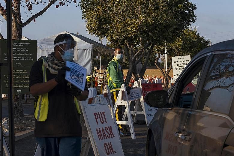 Workers guiding vehicles at the entrance of the Covid-19 drive-through testing site at the Crenshaw Christian Centre in Los Angeles on Friday. The US Food and Drug Administration on Friday authorised the vaccine for emergency use, after Britain becam