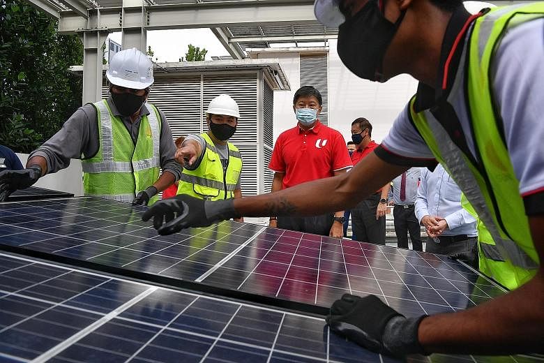 NTUC secretary-general Ng Chee Meng observing workers install a solar panel at the Singapore Sustainability Academy yesterday. The Employment and Employability Institute and Sustainable Energy Association of Singapore signed deals with nine solar fir