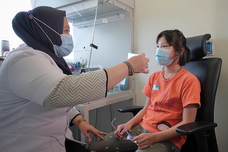 National University Hospital ocularist Suriya Abu Waled checking Claire Lim's eye prosthesis at her clinic in the NUH Medical Centre last Friday. Claire, 10, was born with one eye abnormally small and dysfunctional.