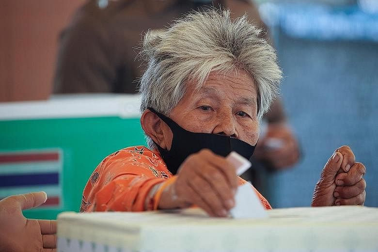 A woman casting her vote at a polling station in Prachuap Khiri Khan province yesterday. Polling officials reported a steady voter turnout. PHOTO: REUTERS People looking for their names on voter lists at a polling station in Prachuap Khiri Khan provi