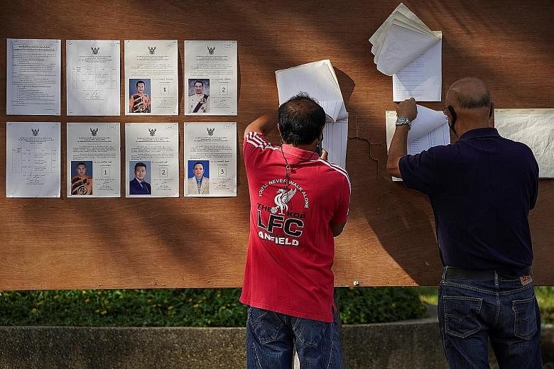 A woman casting her vote at a polling station in Prachuap Khiri Khan province yesterday. Polling officials reported a steady voter turnout. PHOTO: REUTERS People looking for their names on voter lists at a polling station in Prachuap Khiri Khan provi