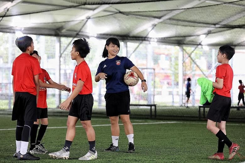 FootballPlus coach Ho Wen Jin chatting with players during a water break at a training session last Friday at the New Charis Mission. ST PHOTO: JOEL CHAN