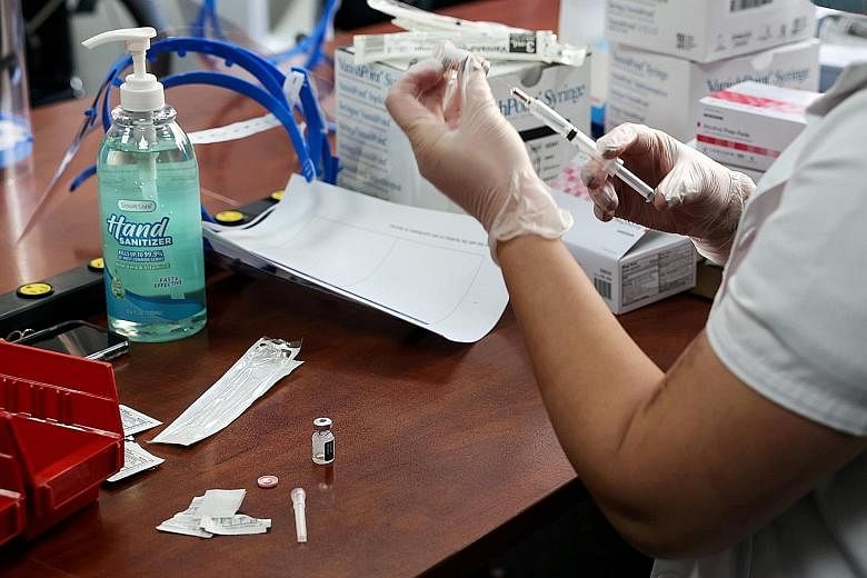 A pharmacist preparing a Pfizer-BioNTech Covid-19 vaccine in New York on Tuesday. A survey by the Nanyang Technological University showed that older respondents in Singapore were more likely to believe a false claim that Covid-19 vaccines alter DNA, 