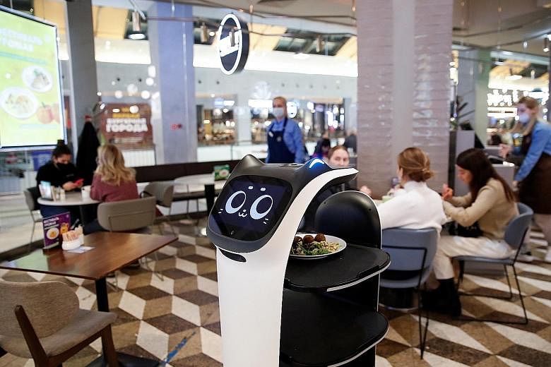 Customers at a cafe in Moscow which is using a robotic waiter to provide contactless service amid the Covid-19 outbreak. But complex and emotionally difficult tasks are still best handled by front-line staff. PHOTO: REUTERS