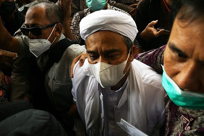 FPI leader Rizieq Shihab surrounded by his supporters as he arrived at the police headquarters in Jakarta on Dec 12, after being summoned by the authorities.