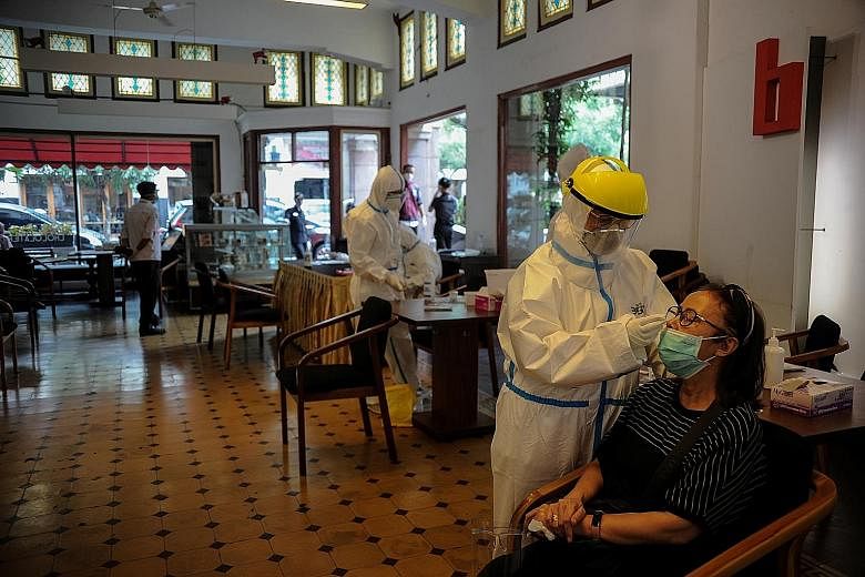 A healthcare worker taking a rapid antigen sample from a woman in Bandung, West Java province, in Indonesia, on Wednesday. The country is set to receive raw materials to produce 15 million doses of vaccine from Chinese firm Sinovac Biotech soon. Indo