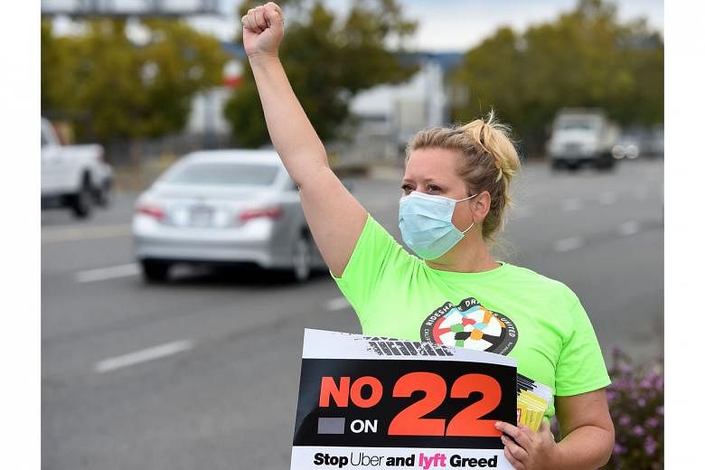 Ride-sharing driver Erica Mighetto holding up a sign supporting a "no" vote on Proposition 22 - a referendum to overturn a state law that would have forced gig firms to recognise their drivers as employees - in California in October last year. Califo