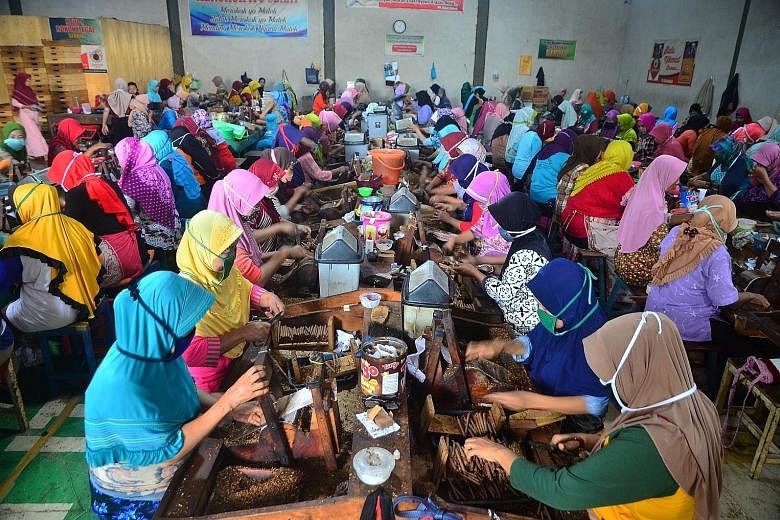 Workers rolling cigarettes in an Indonesian factory. To curb the vice, the tobacco excise tax will be raised next month. PHOTO: REUTERS