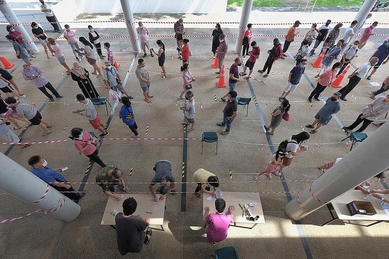 Left: Residents queueing to collect their TraceTogether tokens at Kampong Kembangan Community Club last month. Above: Education Minister Lawrence Wong, who co-chairs the multi-ministry task force in charge of tackling the Covid-19 crisis, said the Go