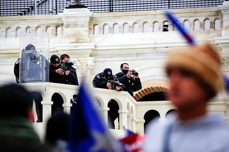 Above: Law enforcement officers aiming less lethal weapons at pro-Trump protesters on Wednesday at the US Capitol. Left: The protesters broke into the building to protest against President Donald Trump's election defeat, ransacking parts of it while 