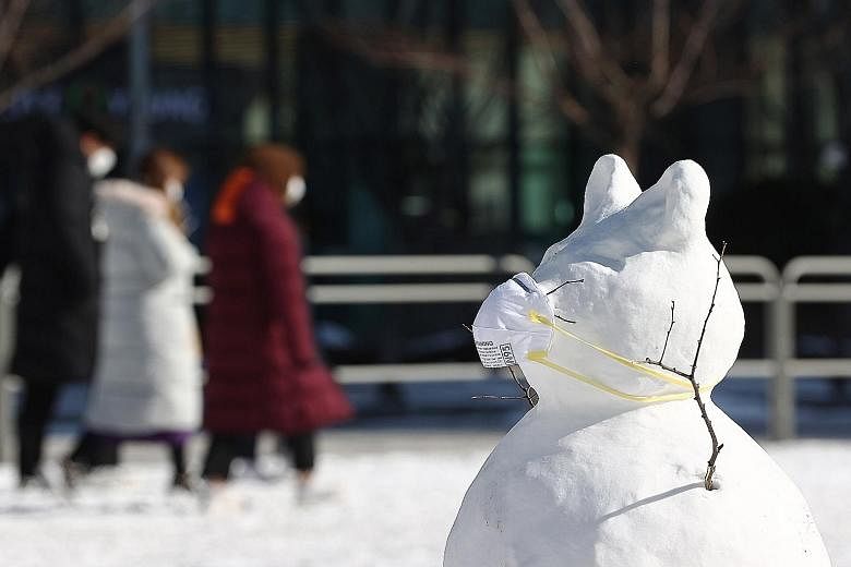 A masked snowman standing in front of an outdoor Covid-19 testing station in Seoul yesterday, as heavy snowfall hit South Korea. Some experts attributed the cold weather to a lower carbon footprint last year, with factories shutting down during the c