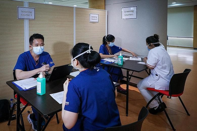 Healthcare workers doing a pre-consultation before the Covid-19 vaccination at Singapore General Hospital yesterday. The Government will consider relaxing stay-home measures for vaccinated travellers if the vaccines prove to significantly curb the sp
