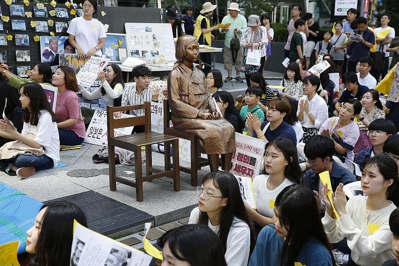 A 2019 photo of South Korean supporters of wartime comfort women sitting around a statue symbolising the sex slaves at a rally in Seoul against the Japanese government. A South Korean court yesterday ordered Japan to make financial reparations of 100