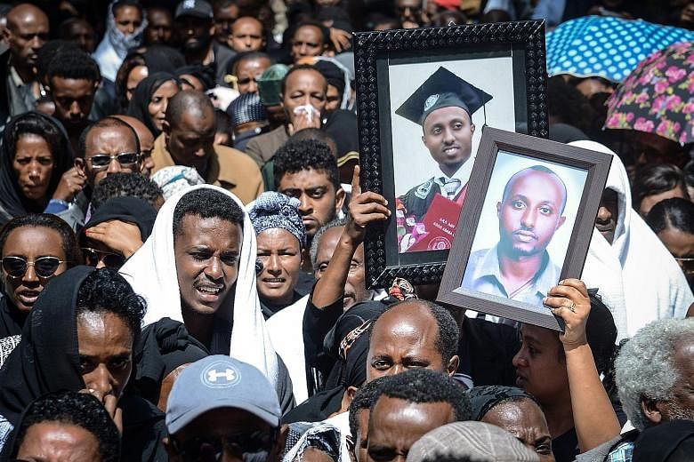 Mourners carrying portraits of victims in the Ethiopian Airlines Flight 302 crash, which killed all 157 people on board, during a mass funeral in Addis Ababa, Ethiopia, in March 2019. PHOTO: AGENCE FRANCE-PRESSE