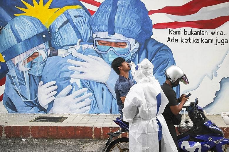 A medical worker taking a swab sample for Covid-19 testing yesterday from a man on a motorbike at Ajwa clinic in Shah Alam, Selangor. The movement control order kicks in in Selangor and four other Malaysian states tomorrow.