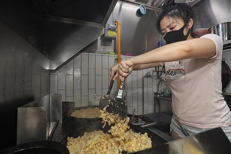 Ms Elayne Ang cooking carrot cake at her stall, Tian Kee Carrot Cake and Hokkien Mee, in Marine Parade Central. She had worked for more than 15 years in the banking industry before making the switch to the hawker trade in 2019. Yesterday, she receive