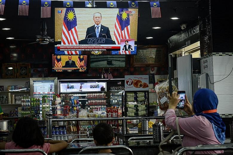 Kuala Lumpur residents watching yesterday's live national address by Prime Minister Muhyiddin Yassin where he announced the state of emergency and sought to instil calm, saying that the government and public services would continue to function normal