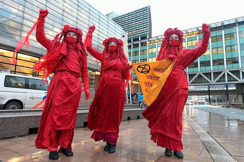 Environmental activists protesting in The Hague, Netherlands, during the hearing of a case that environmentalist and human rights groups brought against Royal Dutch Shell, to force the energy firm to cut its reliance on fossil fuels, on Dec 1. The ba