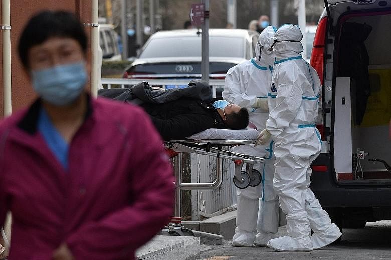 Medical workers wearing protective suits moving a patient to the fever clinic at a hospital in Beijing yesterday. Most of the new patients were reported near the capital city, but a province in north-east China also saw a rise in new cases. There wer