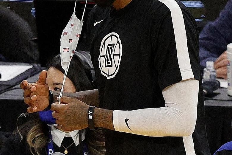 Clippers guard Paul George taking off his mask before checking back into the game against the Warriors at Chase Centre. NBA players must wear masks on the bench at all times.