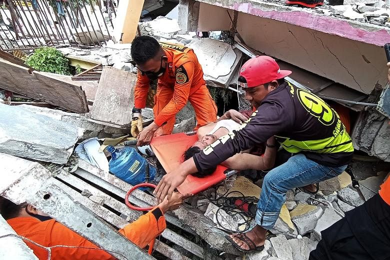 Rescuers evacuating a man from a building that collapsed in Mamuju, West Sulawesi, yesterday. PHOTO: REUTERS Rescuers (left) searching for survivors at the site of a collapsed building in Mamuju city. A hospital (right) in the Indonesian city was als