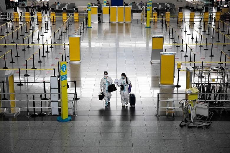 Travellers in protective suits at the Ninoy Aquino International Airport in Metro Manila on Thursday. The Philippines' ban on all travellers from more than 30 countries and territories where a more contagious coronavirus variant has been detected, wh
