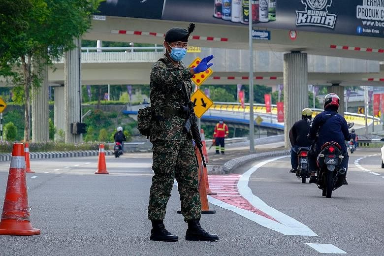 A soldier at a checkpoint in Kuala Lumpur on Wednesday. A surge in new coronavirus cases yesterday saw Malaysia extending its stringent movement controls to a sixth state, Kelantan. PHOTO: BLOOMBERG