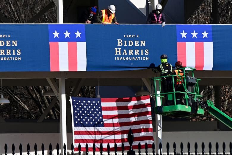 National Guard soldiers with crates of rifles on the grounds of the US Capitol building in Washington on Thursday. Workers placing Biden-Harris inauguration banners on the parade viewing stand across from the White House in Washington on Thursday.